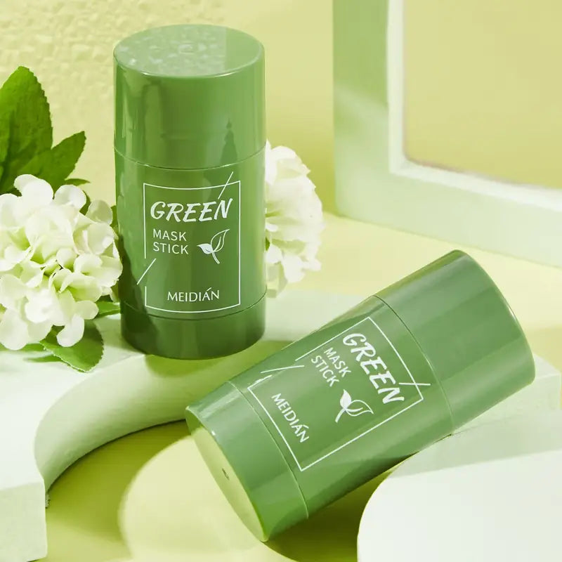 Two Steep green tea mask sticks resting on a pale green stand beside white flowers